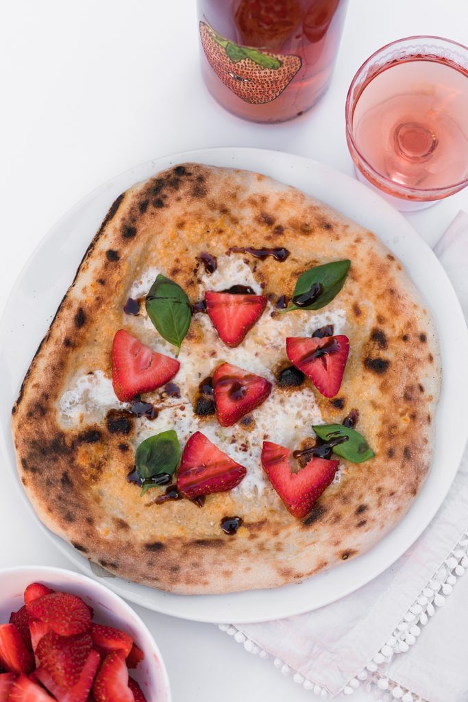 Strawberry pizza with strawberry wine on table