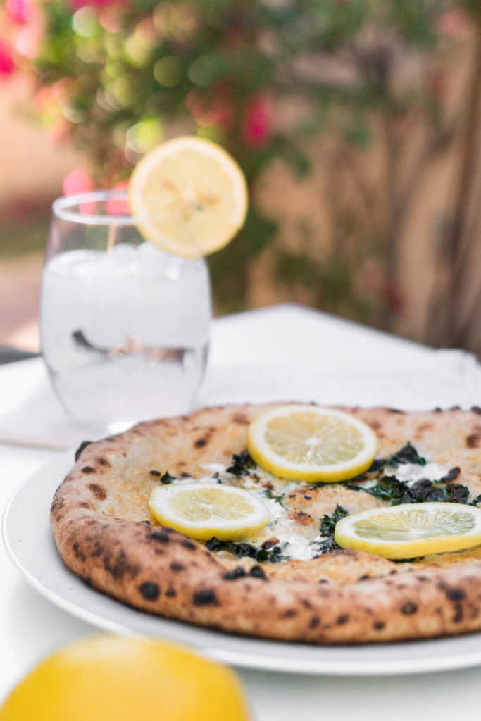 Kale lemon pizza displayed outdoors with water